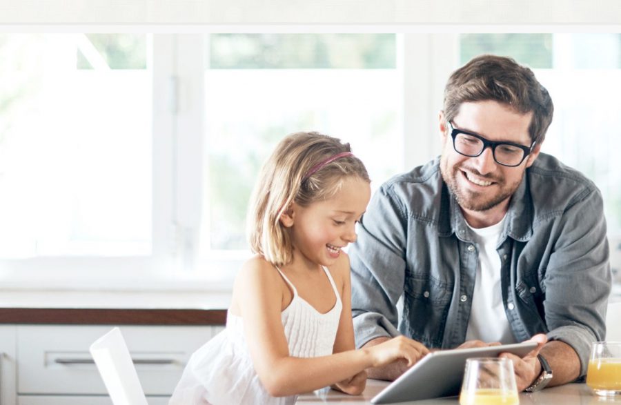 Middle-aged man and young girl looking at a tablet, smiling